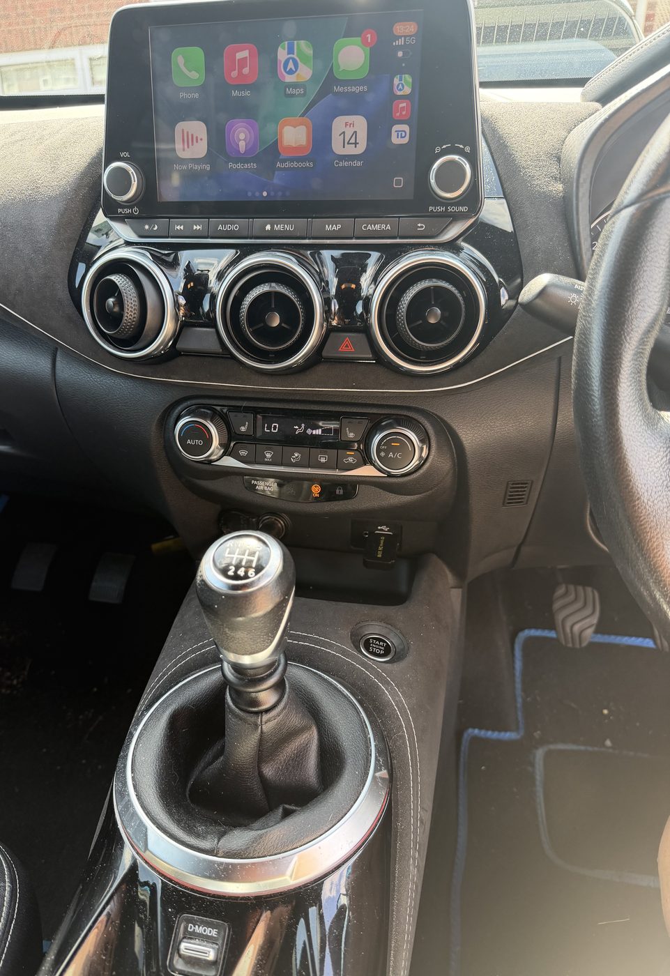 The blue Juke's dashboard and manual gear stick, with Apple CarPlay on the screen